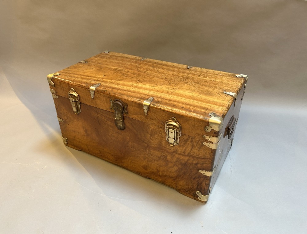 A rectangular solid camphor wood steamer trunk featuring metal corner brackets, metal latches, and side carrying handles.