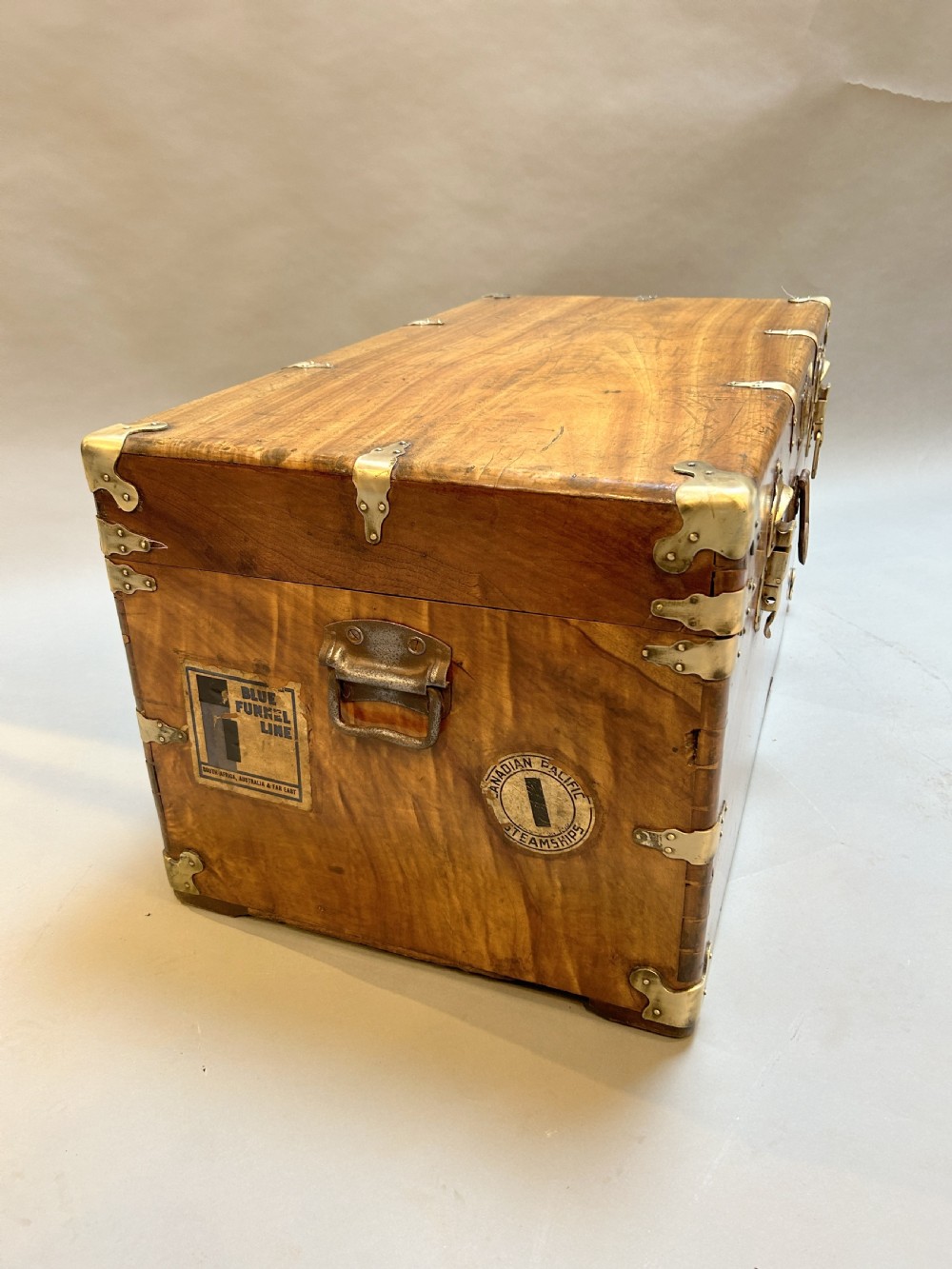 A rectangular solid camphor wood steamer trunk featuring metal corner brackets, metal latches, and side carrying handles. View III