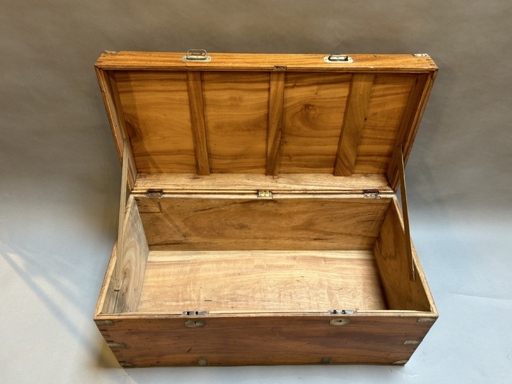 A rectangular 19th-century camphor wood campaign trunk featuring corner brass bindings, flush-fitting handles, and keyhole escutcheons. View V