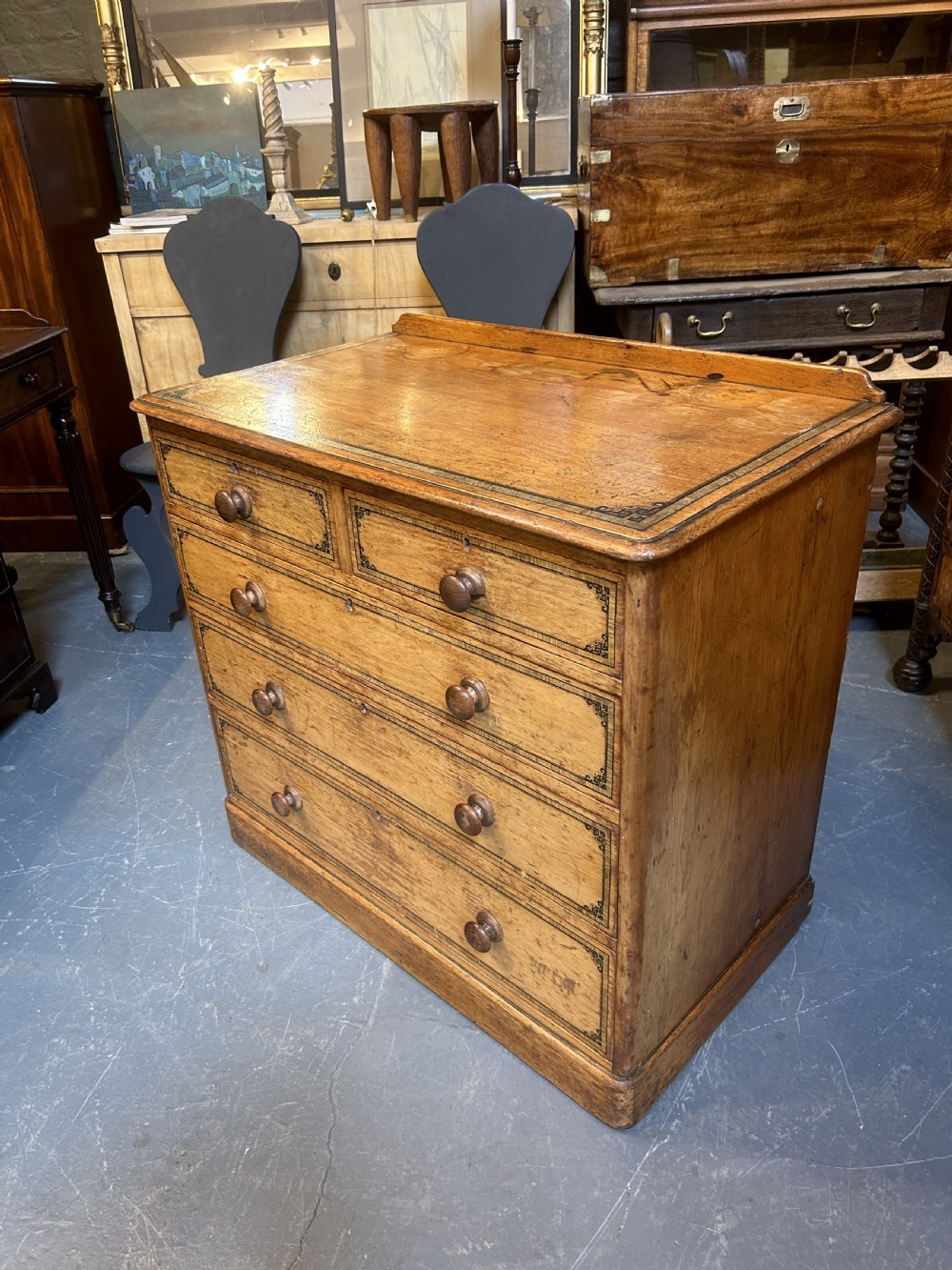 A Victorian pine chest of drawers with black stencilled borders, featuring two short drawers over three long drawers with turned wooden knobs. View V