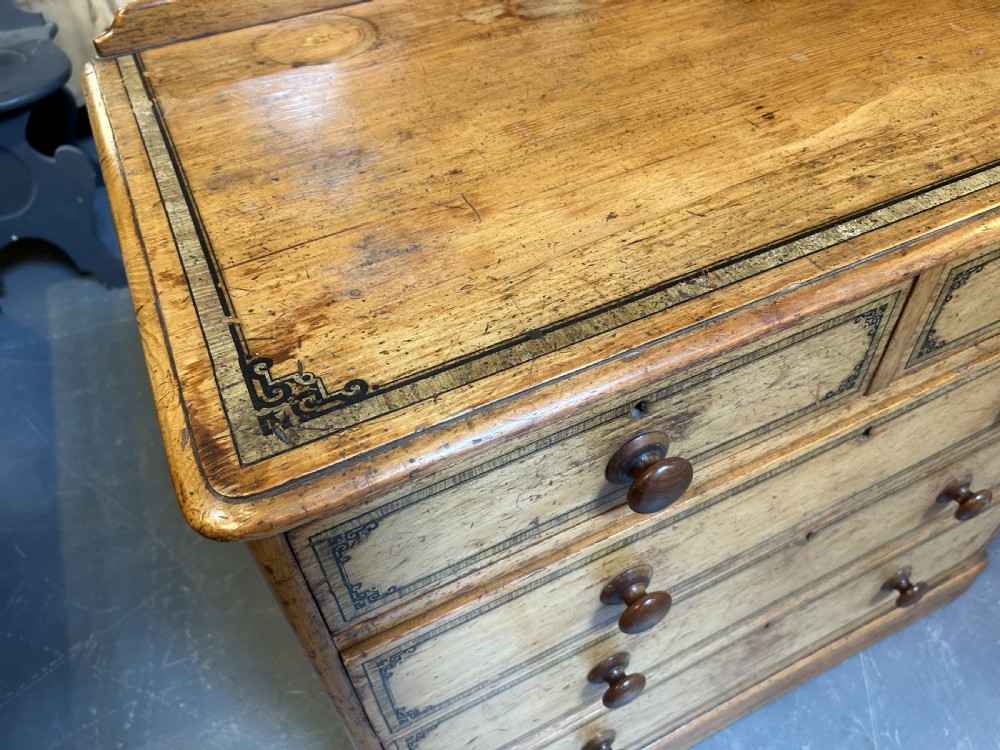 A Victorian pine chest of drawers with black stencilled borders, featuring two short drawers over three long drawers with turned wooden knobs. View VII