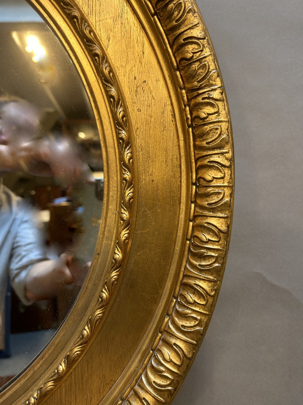 A circular Victorian wall mirror featuring a carved gold gilt frame with moulded gadrooned detail. View III