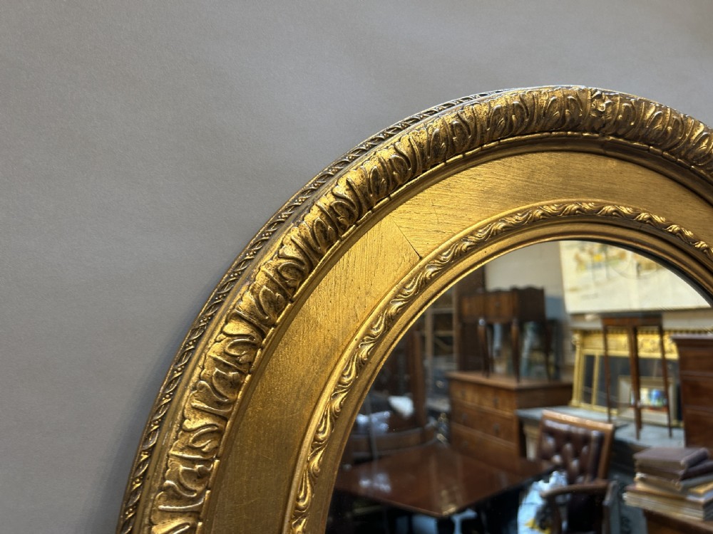 A circular Victorian wall mirror featuring a carved gold gilt frame with moulded gadrooned detail. View IV