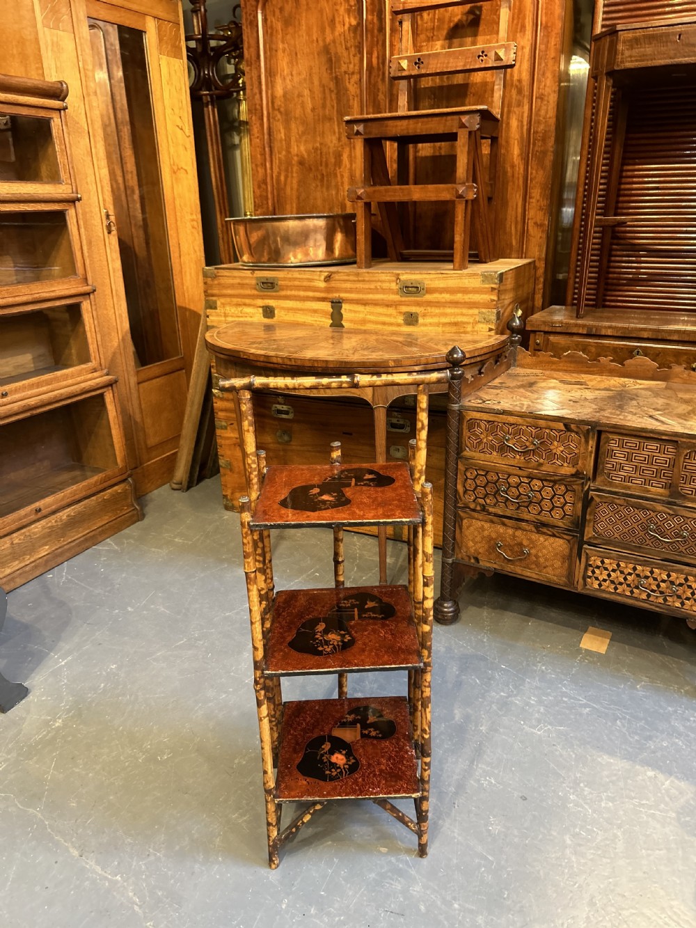 A three-tiered late Victorian bamboo side table featuring a mottled finish, square lacquered shelves decorated with fan motifs, and an overarching top handle. View III