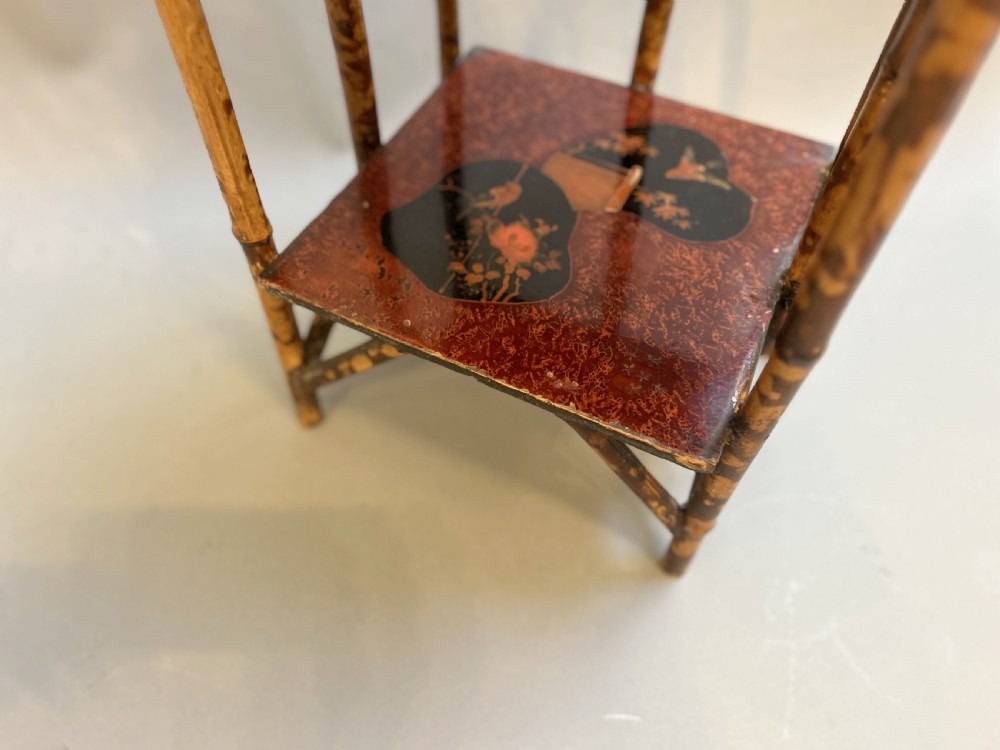 A three-tiered late Victorian bamboo side table featuring a mottled finish, square lacquered shelves decorated with fan motifs, and an overarching top handle. View IV