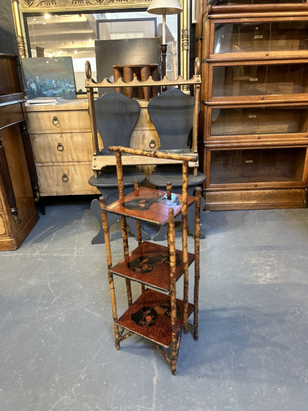 A three-tiered late Victorian bamboo side table featuring a mottled finish, square lacquered shelves decorated with fan motifs, and an overarching top handle. View V