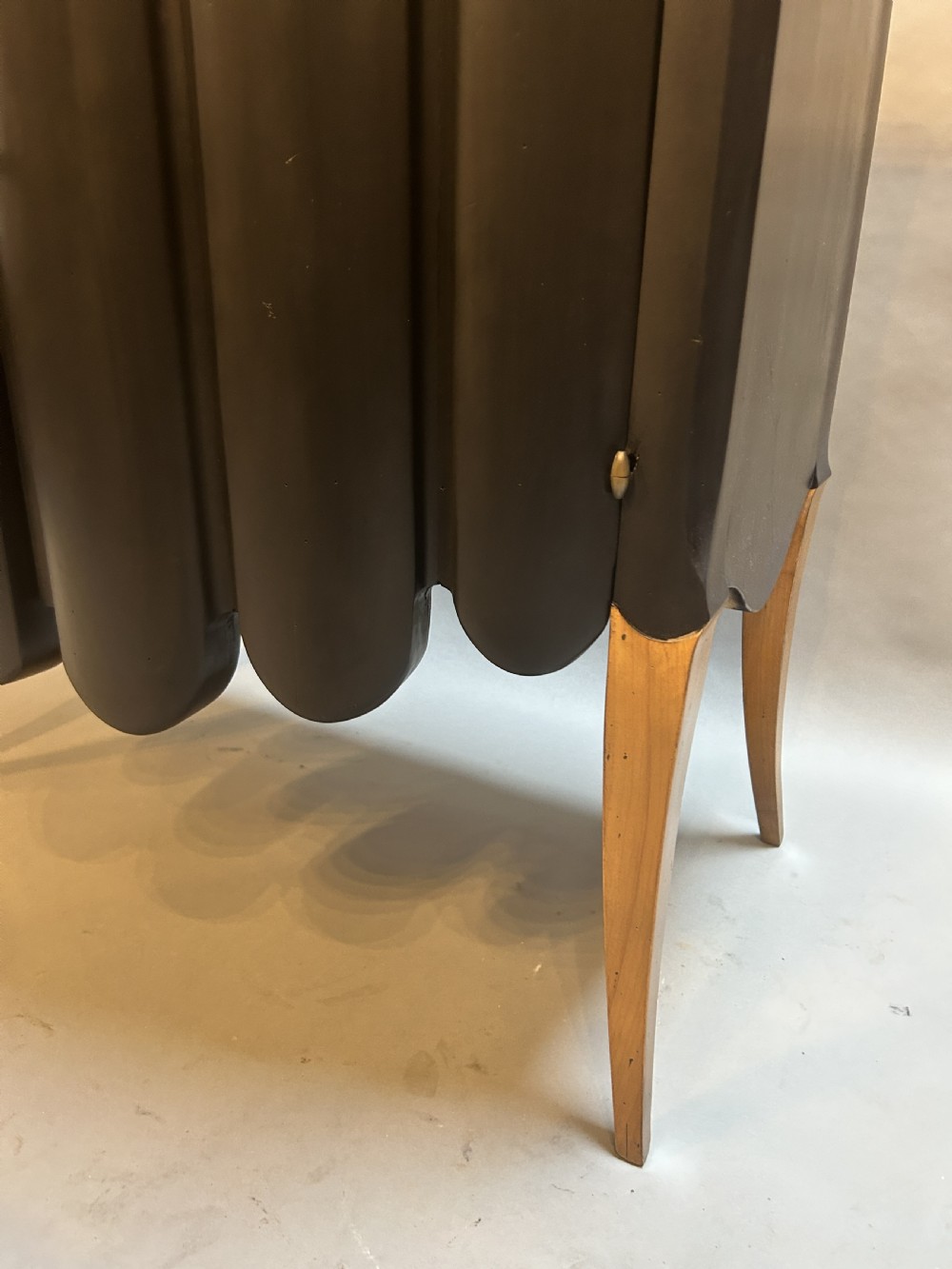 A French Art Deco black ebonised side cabinet with fluted doors, brass key hardware, and tapered light-coloured legs. View III