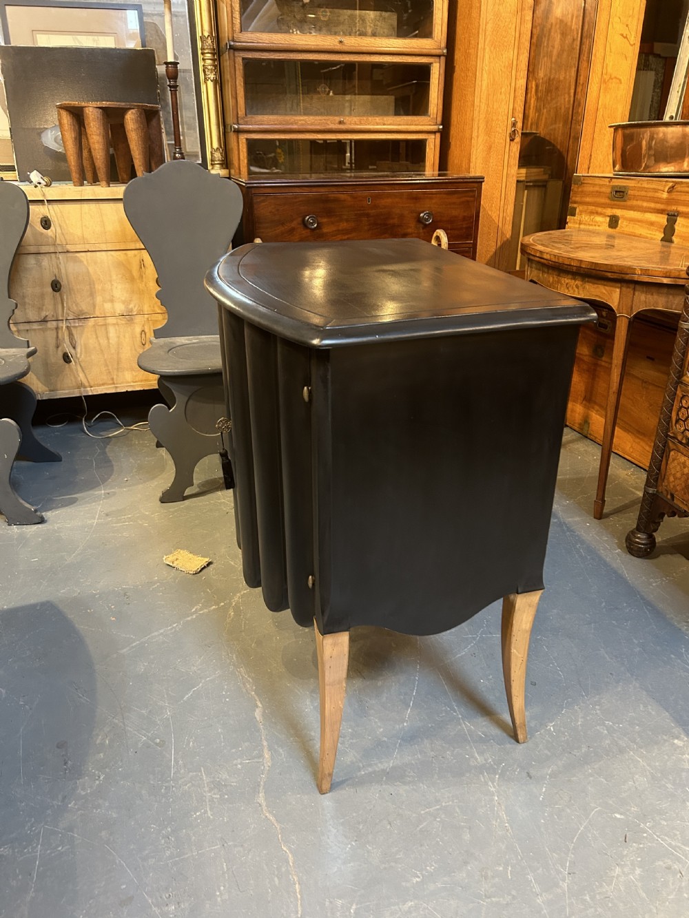 A French Art Deco black ebonised side cabinet with fluted doors, brass key hardware, and tapered light-coloured legs. View VII