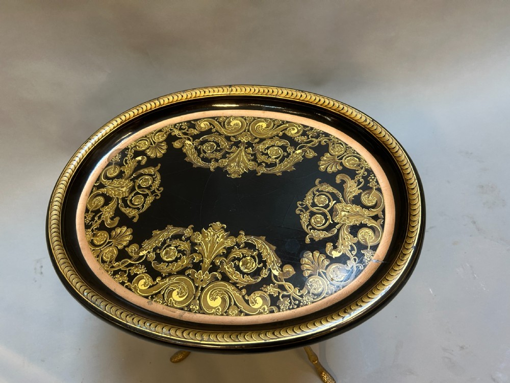 An oval black lacquered papier-mache tray table with detailed gilt scrollwork, supported on a brass faux-bamboo base with an X-stretcher. View II