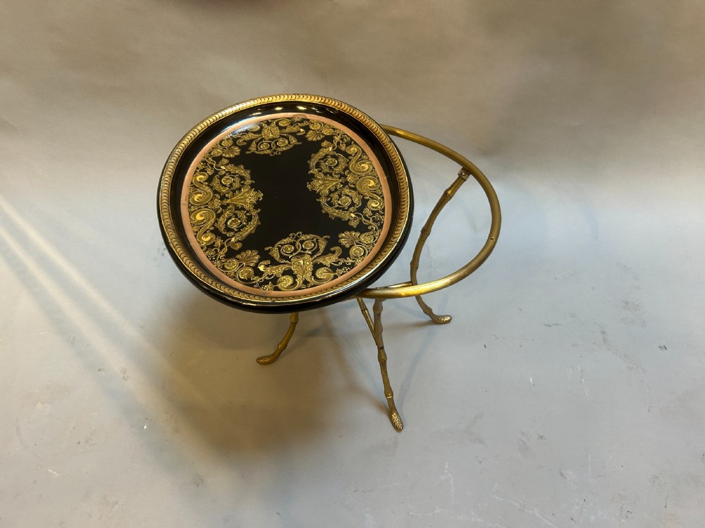 An oval black lacquered papier-mache tray table with detailed gilt scrollwork, supported on a brass faux-bamboo base with an X-stretcher. View III