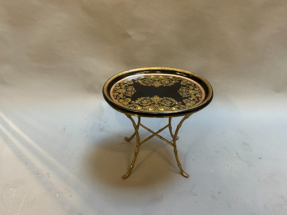 An oval black lacquered papier-mache tray table with detailed gilt scrollwork, supported on a brass faux-bamboo base with an X-stretcher. View V