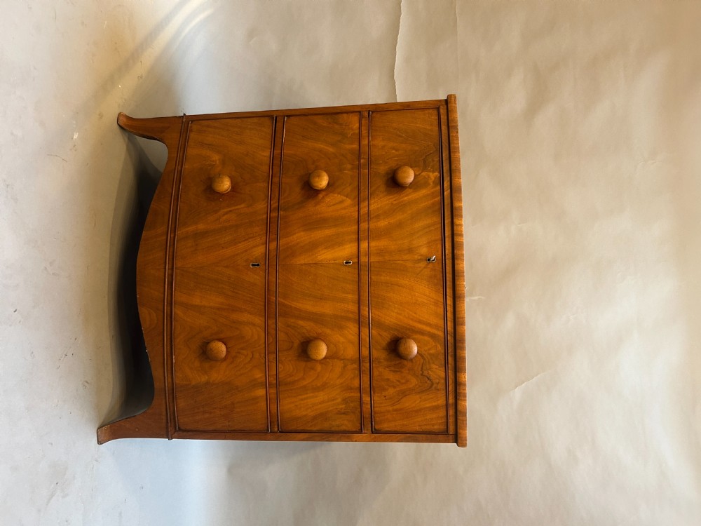 A George III bow front chest of drawers in warm brown timber, featuring three graduated drawers with turned wooden handles and splayed feet. View VII