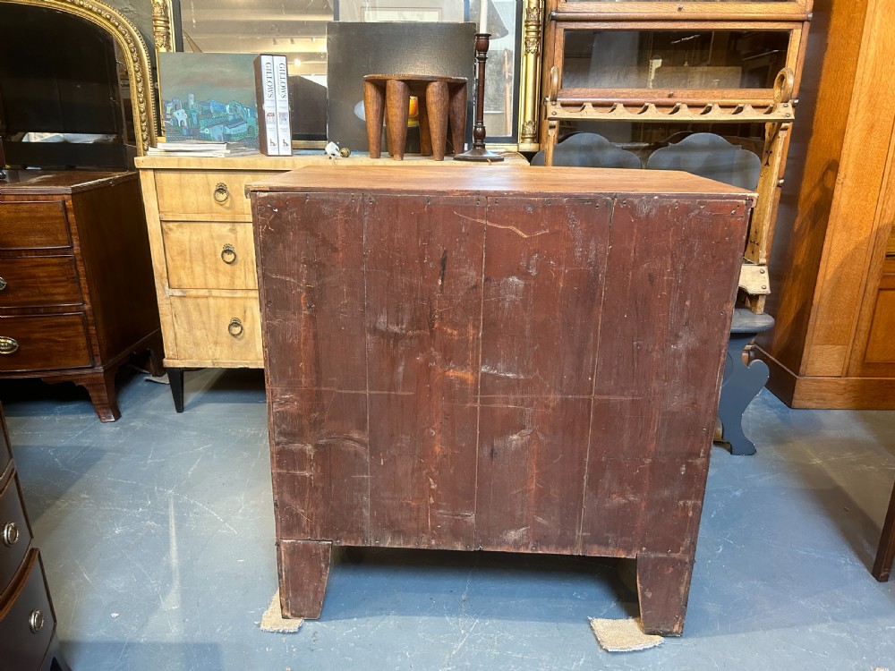 A George III bow front chest of drawers in warm brown timber, featuring three graduated drawers with turned wooden handles and splayed feet. View X