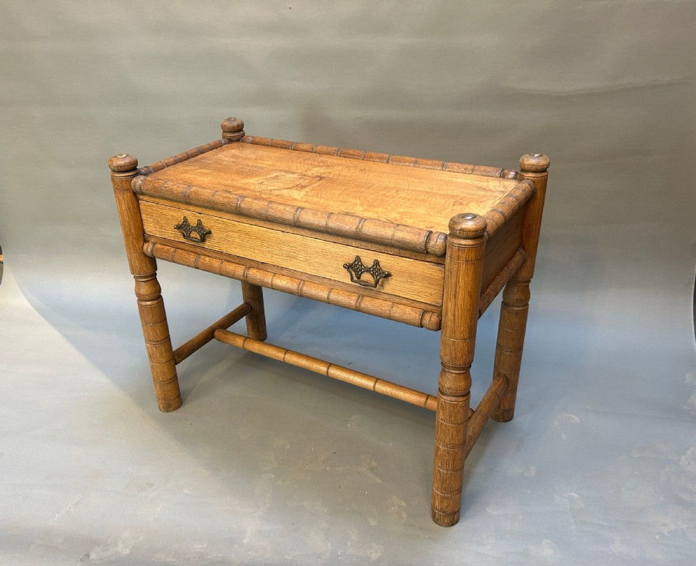 A 19th-century medium oak side table featuring ring-turned legs, a single drawer with brass drop handles, and a raised turned wooden gallery edge.