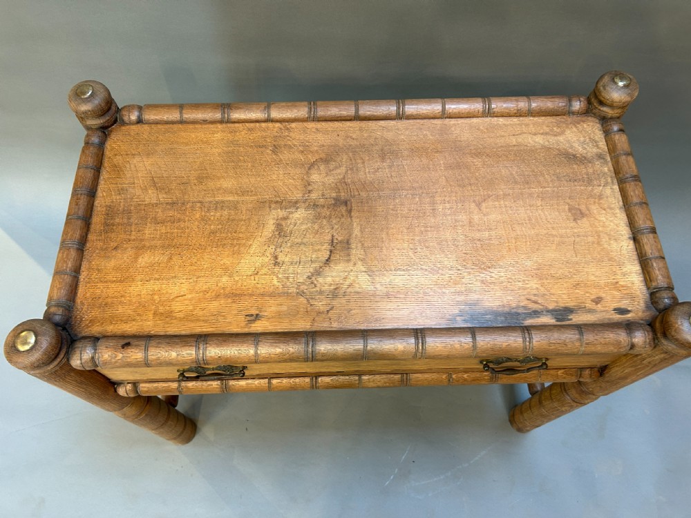 A 19th-century medium oak side table featuring ring-turned legs, a single drawer with brass drop handles, and a raised turned wooden gallery edge. View III