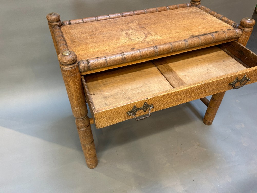 A 19th-century medium oak side table featuring ring-turned legs, a single drawer with brass drop handles, and a raised turned wooden gallery edge. View V