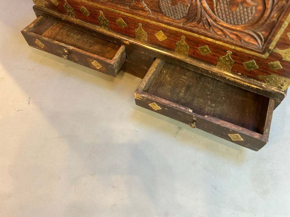 A 19th-century dark hardwood Zanzibar chest featuring relief floral carving, pierced brass plates, brass corner mounts, and three small lower drawers. View III