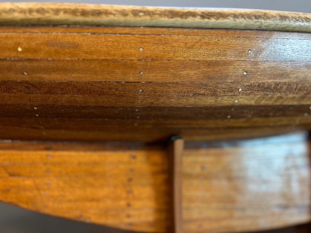 A varnished wooden pond yacht hull supported upright on a custom wooden display stand. View II
