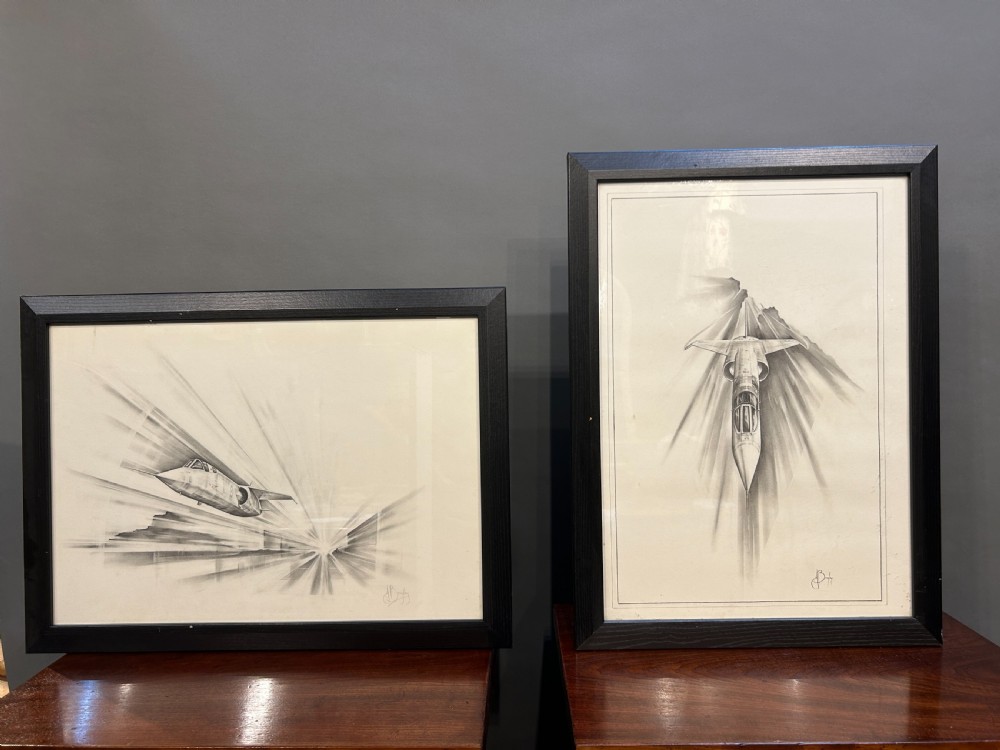 A pair of framed monochrome pencil sketches depicting jet aircraft in high-speed motion, one oriented horizontally and the other vertically.