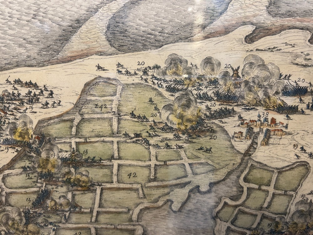 A pair of framed 19th-century prints displaying detailed topographical military formations and coastal maps in matching wooden frames. View III