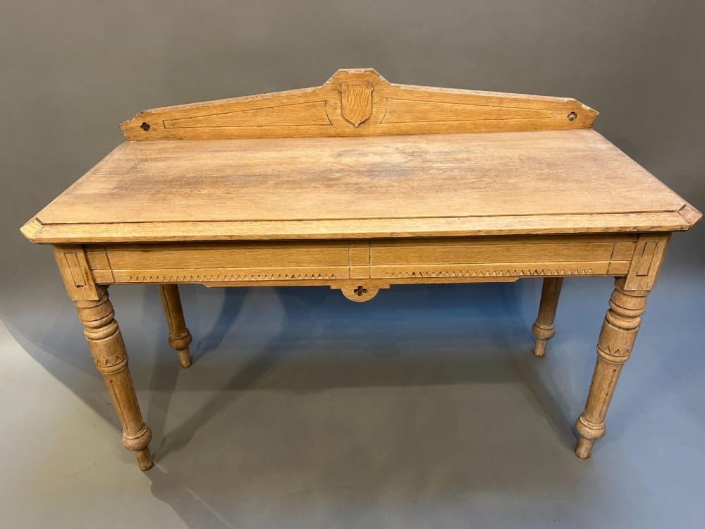 A Victorian light oak hall table featuring a carved upstand with a central shield motif, decorative frieze, and turned legs. View IV