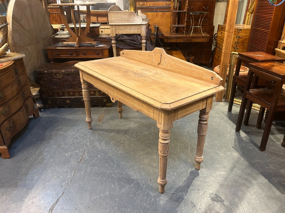A Victorian light oak hall table featuring a carved upstand with a central shield motif, decorative frieze, and turned legs. View VI