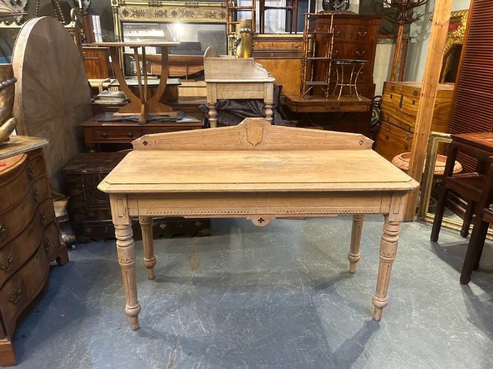 A Victorian light oak hall table featuring a carved upstand with a central shield motif, decorative frieze, and turned legs. View VII