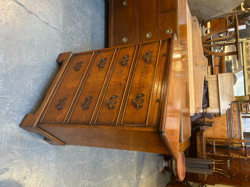 A small Georgian Revival burr walnut chest of drawers featuring four graduated drawers with brass drop handles and bracket feet. View VI