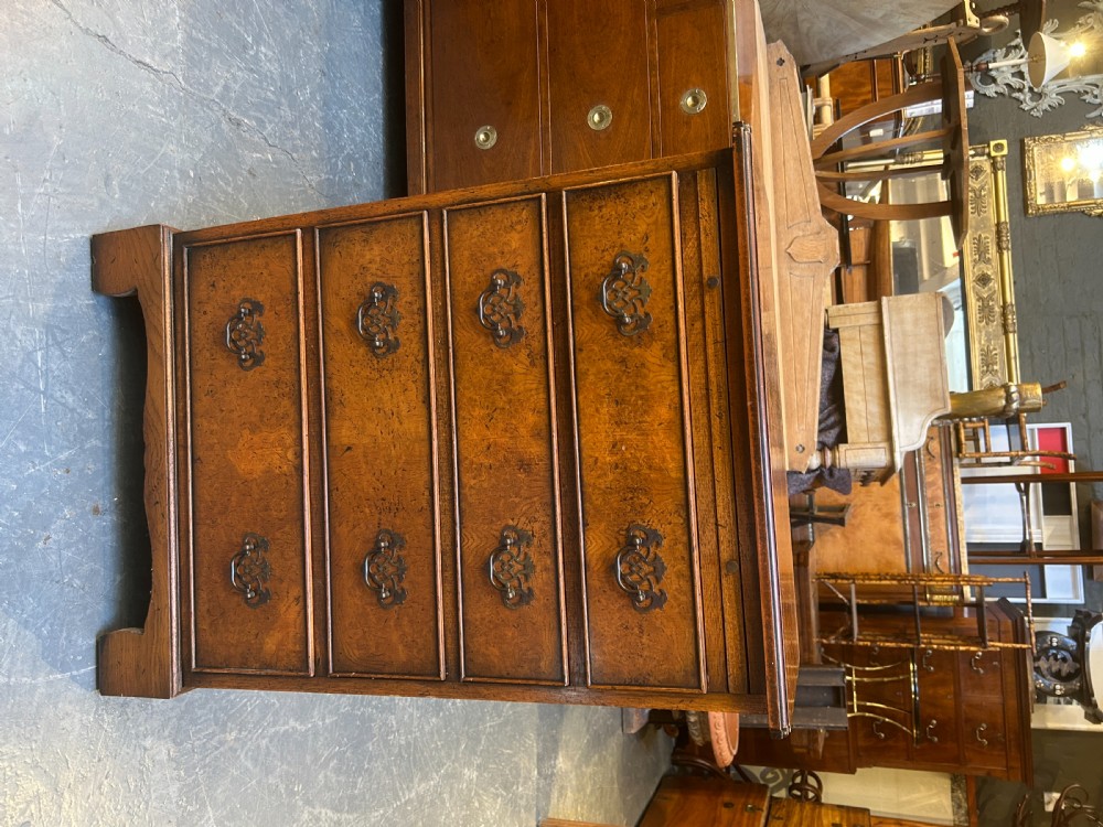 A small Georgian Revival burr walnut chest of drawers featuring four graduated drawers with brass drop handles and bracket feet. View VII