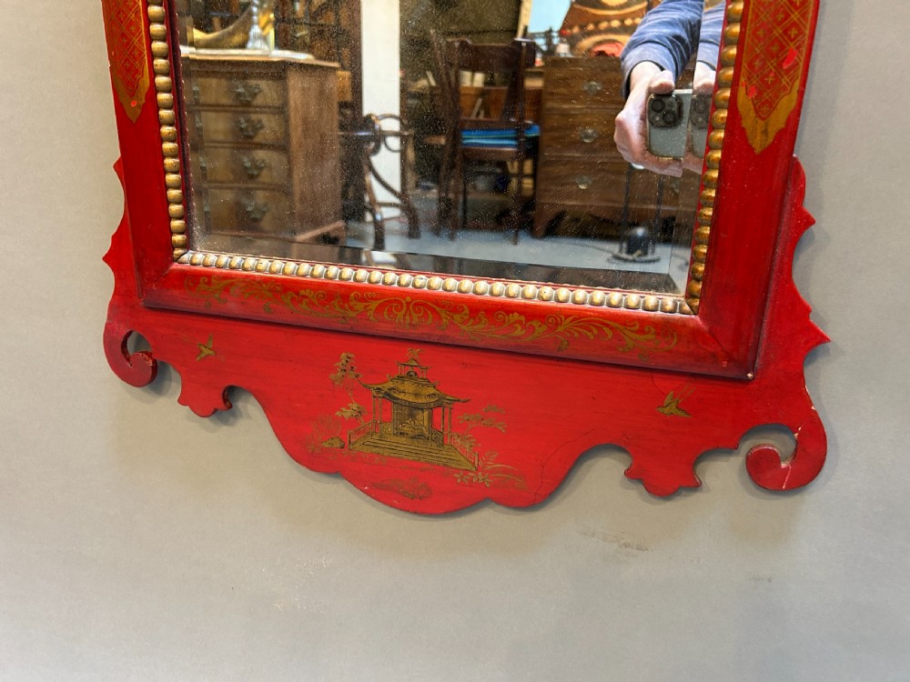 A tall rectangular red lacquered wall mirror featuring intricate gilt Chinoiserie motifs and a scrolled carved pediment. View IV