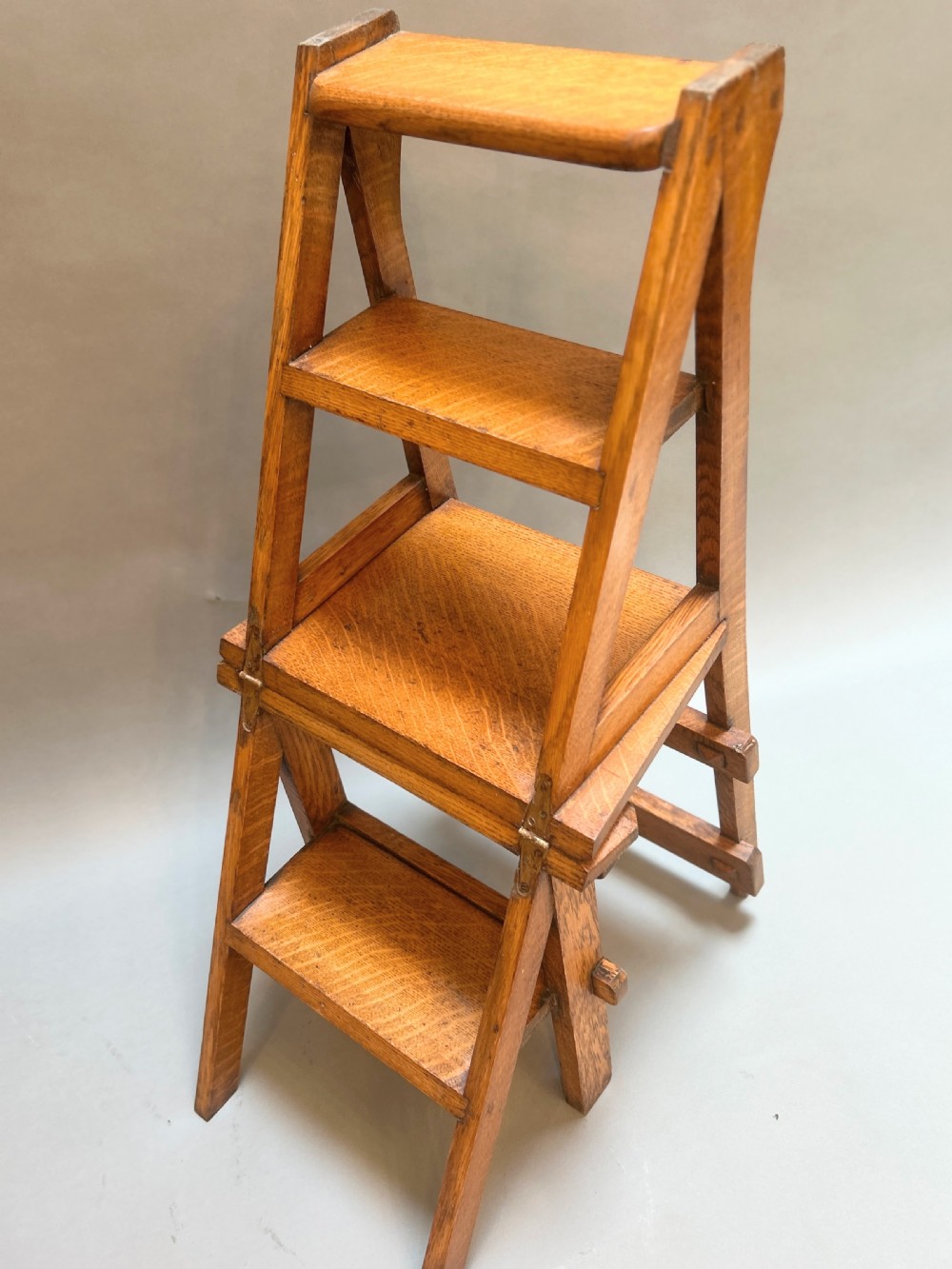 An antique solid oak metamorphic chair that folds into library steps, featuring a pierced trefoil motif backrest and square legs. View VIII