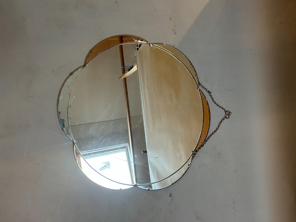 A circular Art Deco wall mirror featuring scalloped outer sectional mirror panels and suspended by a metal hanging chain. View IV