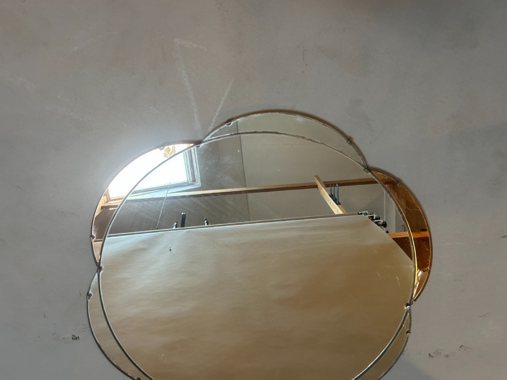 A circular Art Deco wall mirror featuring scalloped outer sectional mirror panels and suspended by a metal hanging chain. View V