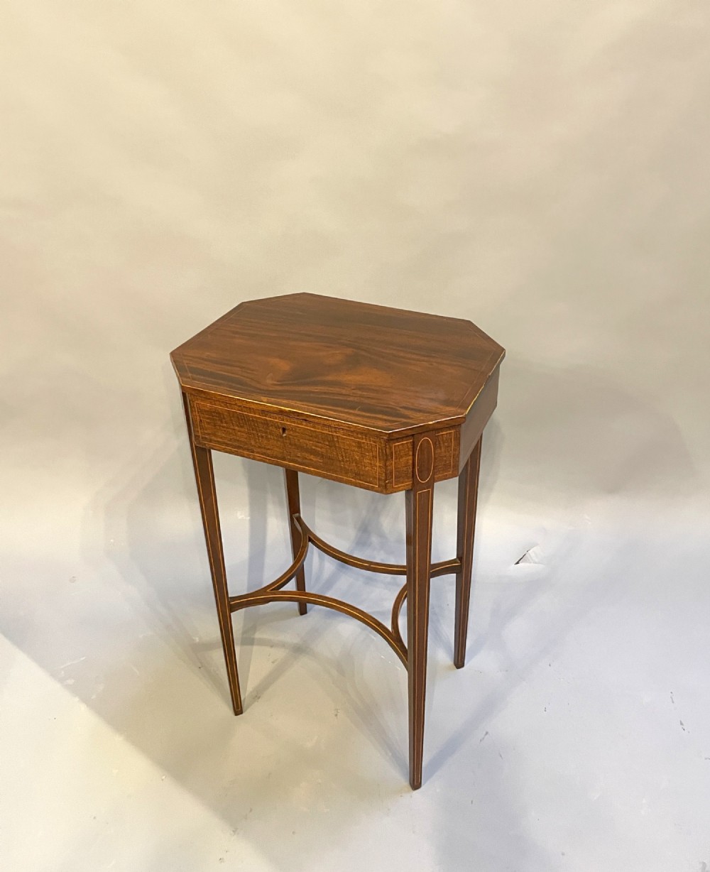 A George IV mahogany occasional lamp table featuring a canted corner top, a single drawer with stringing inlay, and curved X-form stretchers.