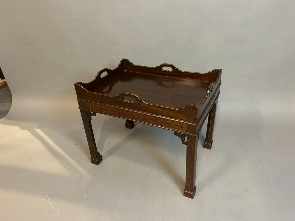 A dark mahogany Georgian style tray top coffee table with integrated side handles, gallery rim, and corner fretwork brackets.