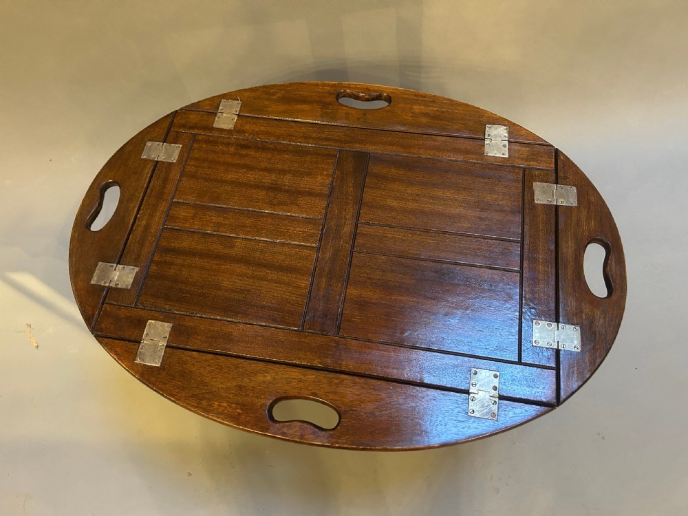An oval dark oak butlers tray coffee table featuring brass-hinged drop sides with cut-out carry handles on a low square-leg base. View II