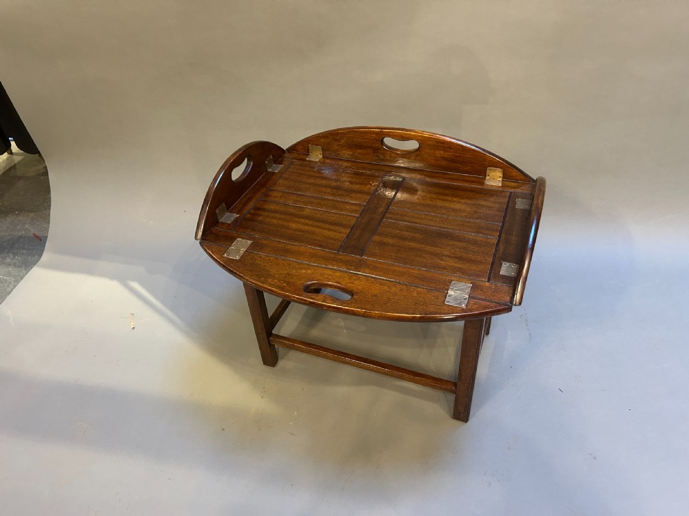 An oval dark oak butlers tray coffee table featuring brass-hinged drop sides with cut-out carry handles on a low square-leg base. View III