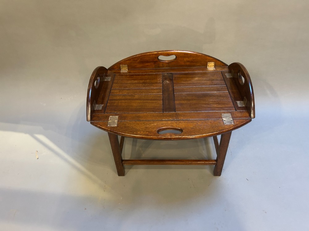 An oval dark oak butlers tray coffee table featuring brass-hinged drop sides with cut-out carry handles on a low square-leg base. View IV
