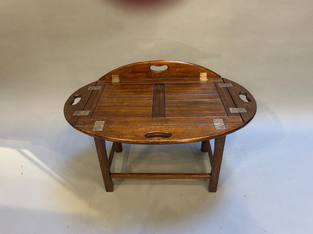 An oval dark oak butlers tray coffee table featuring brass-hinged drop sides with cut-out carry handles on a low square-leg base. View V