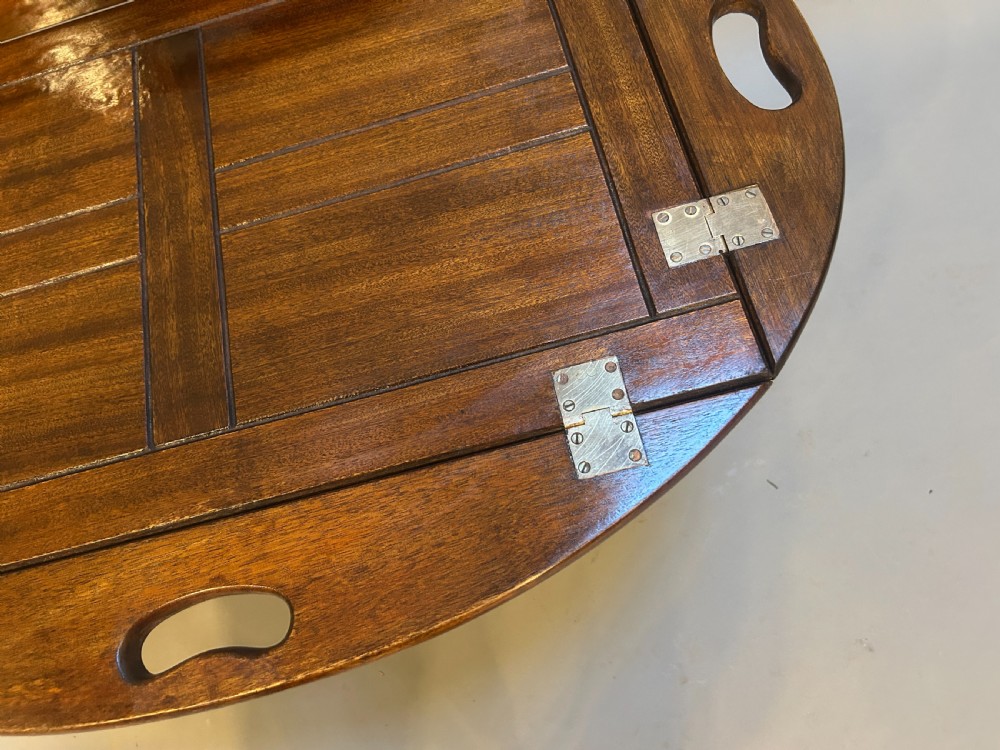 An oval dark oak butlers tray coffee table featuring brass-hinged drop sides with cut-out carry handles on a low square-leg base. View VI