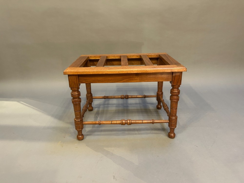 A Victorian wooden luggage stand featuring a slatted top surface supported by four turned legs with horizontal turned stretchers. View V