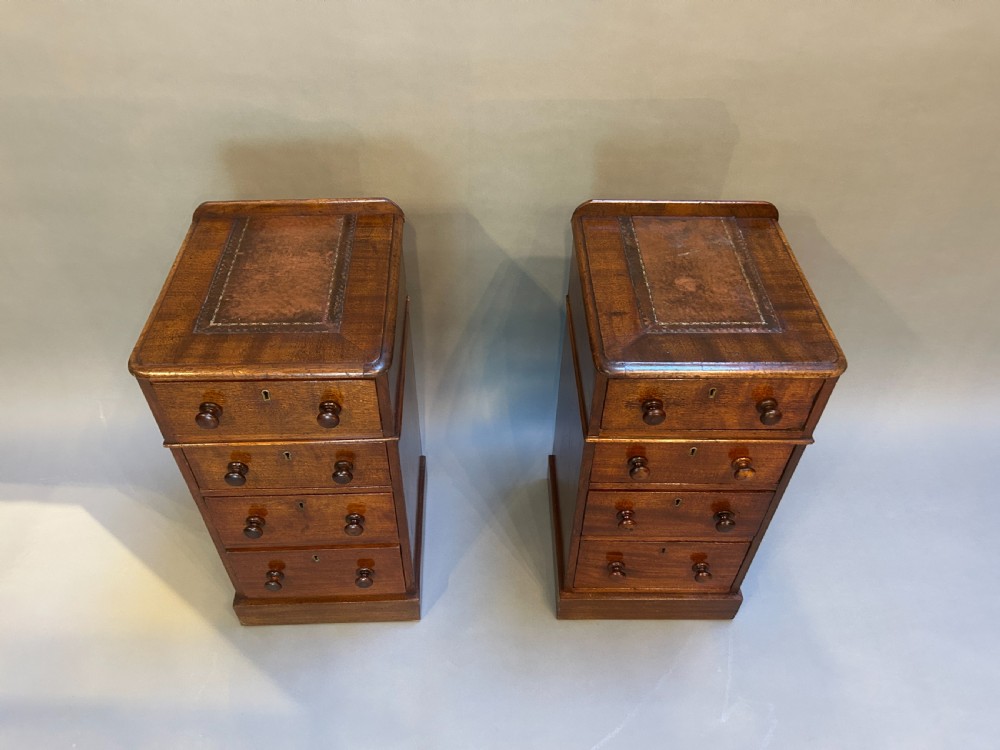 A pair of matching Victorian mahogany narrow bedside chests featuring four drawers with turned wooden knobs and leather inset tops. View II