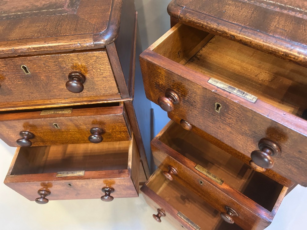 A pair of matching Victorian mahogany narrow bedside chests featuring four drawers with turned wooden knobs and leather inset tops. View V