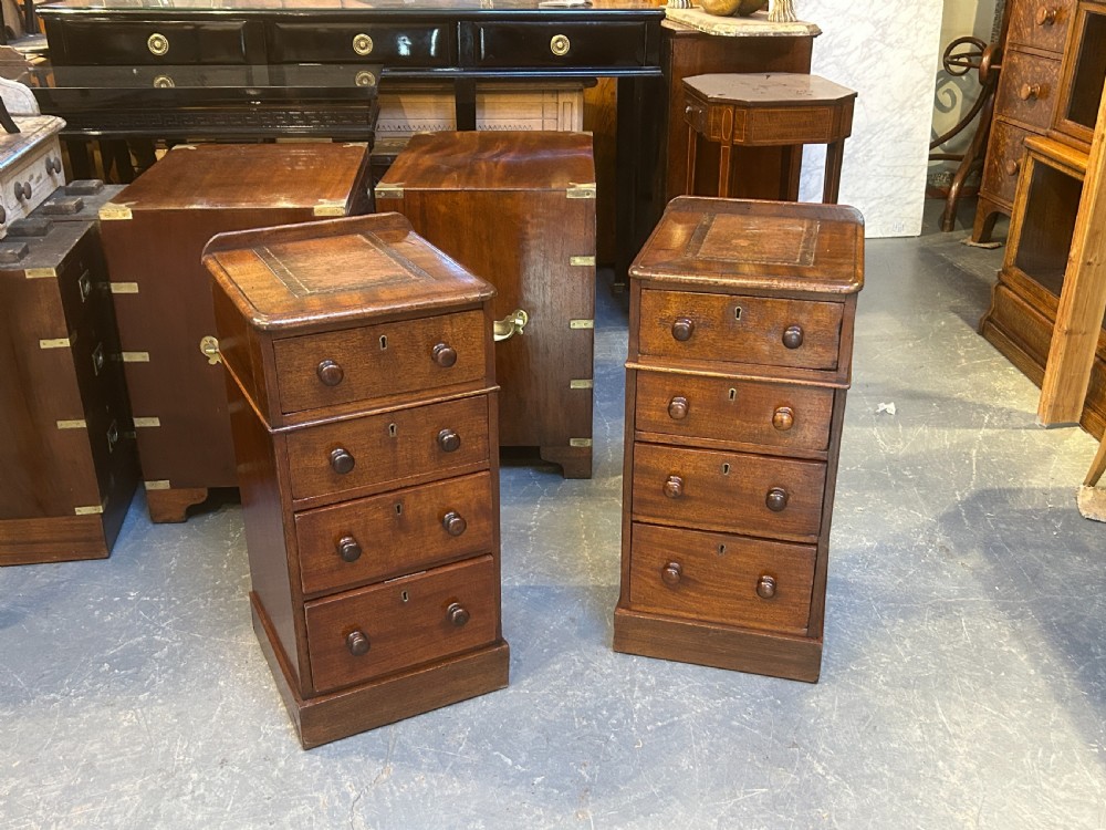 A pair of matching Victorian mahogany narrow bedside chests featuring four drawers with turned wooden knobs and leather inset tops. View IX