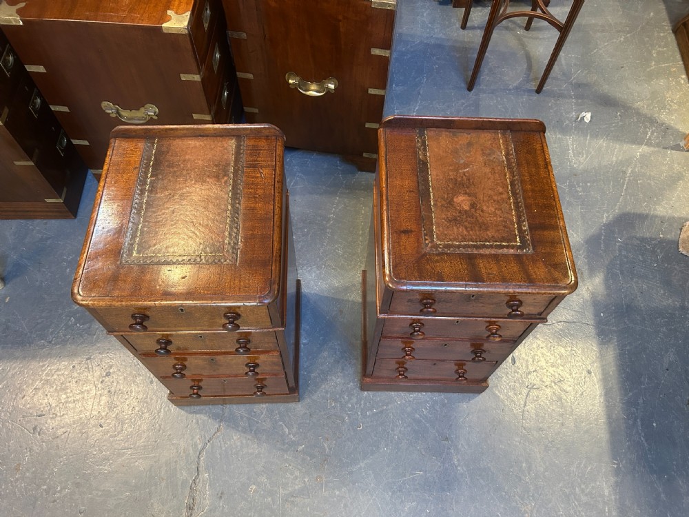 A pair of matching Victorian mahogany narrow bedside chests featuring four drawers with turned wooden knobs and leather inset tops. View X
