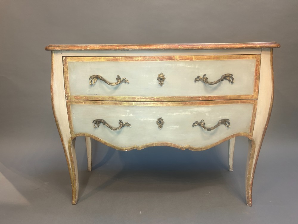 A French Louis XV style painted and gilt serpentine commode featuring two drawers, gold leaf borders, and curved cabriole legs. View IV