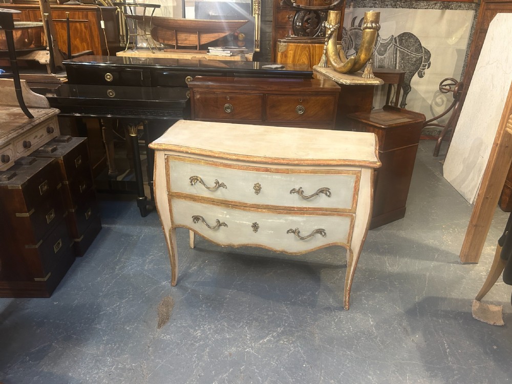 A French Louis XV style painted and gilt serpentine commode featuring two drawers, gold leaf borders, and curved cabriole legs. View VII