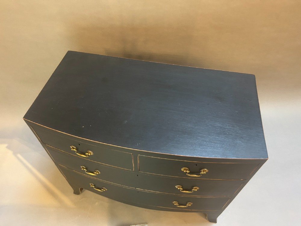 A Regency period ebonised bow-front chest of drawers featuring two short over two long drawers with brass drop handles and bracket feet. View III