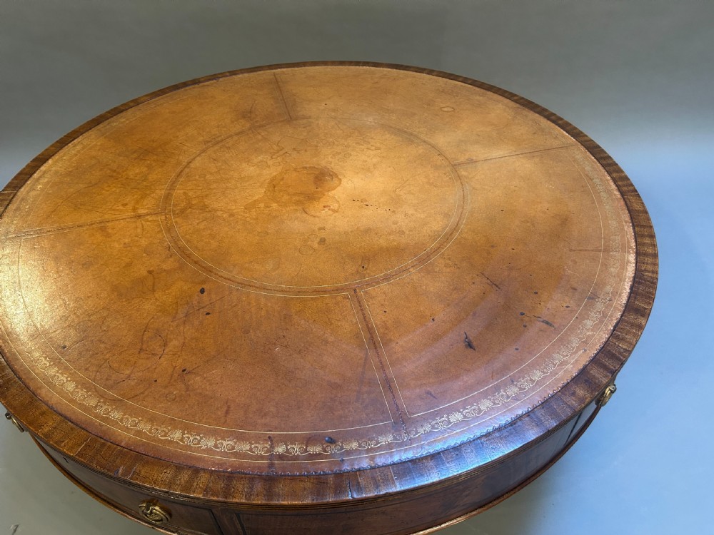 A low circular mahogany drum table featuring a gold-tooled leather top, frieze drawers with brass pulls, and a pedestal base with brass lion paw castors. View III