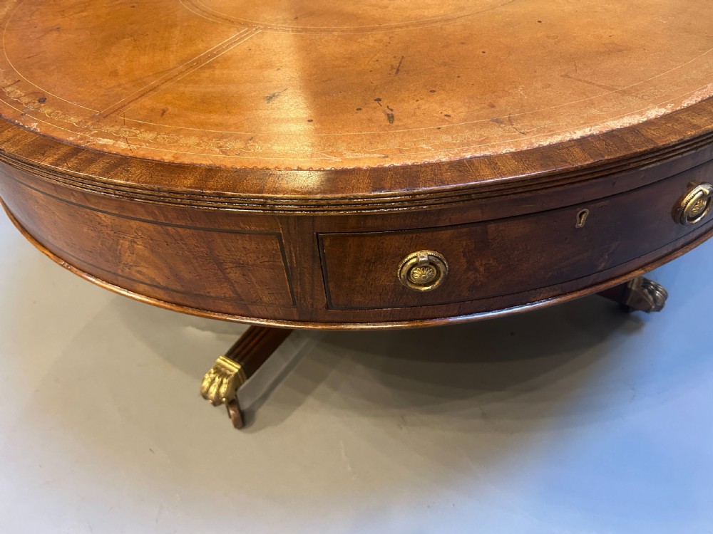 A low circular mahogany drum table featuring a gold-tooled leather top, frieze drawers with brass pulls, and a pedestal base with brass lion paw castors. View IV